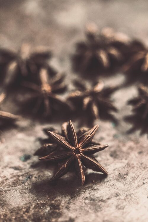 A detailed close-up of star anise spices on a textured, rustic surface with blurred depth of field.